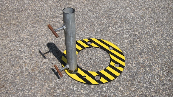 Here's the completed antenna mast support. The yellow and black iron ring is 17 inches in diameter. The galvanized pipe is 17 inches tall and has an ID of 2 inches. Holes were drilled into the side of the pipe so the bolts can secure the mast to eliminate wobble. It's one-half-inch bolt material with a nut welded to the pipe. A small piece of grounding rod is welded to the end of the bolts so you need no tools in the field to secure the antenna mast. Photo credit: Tim Carter - W3ATB